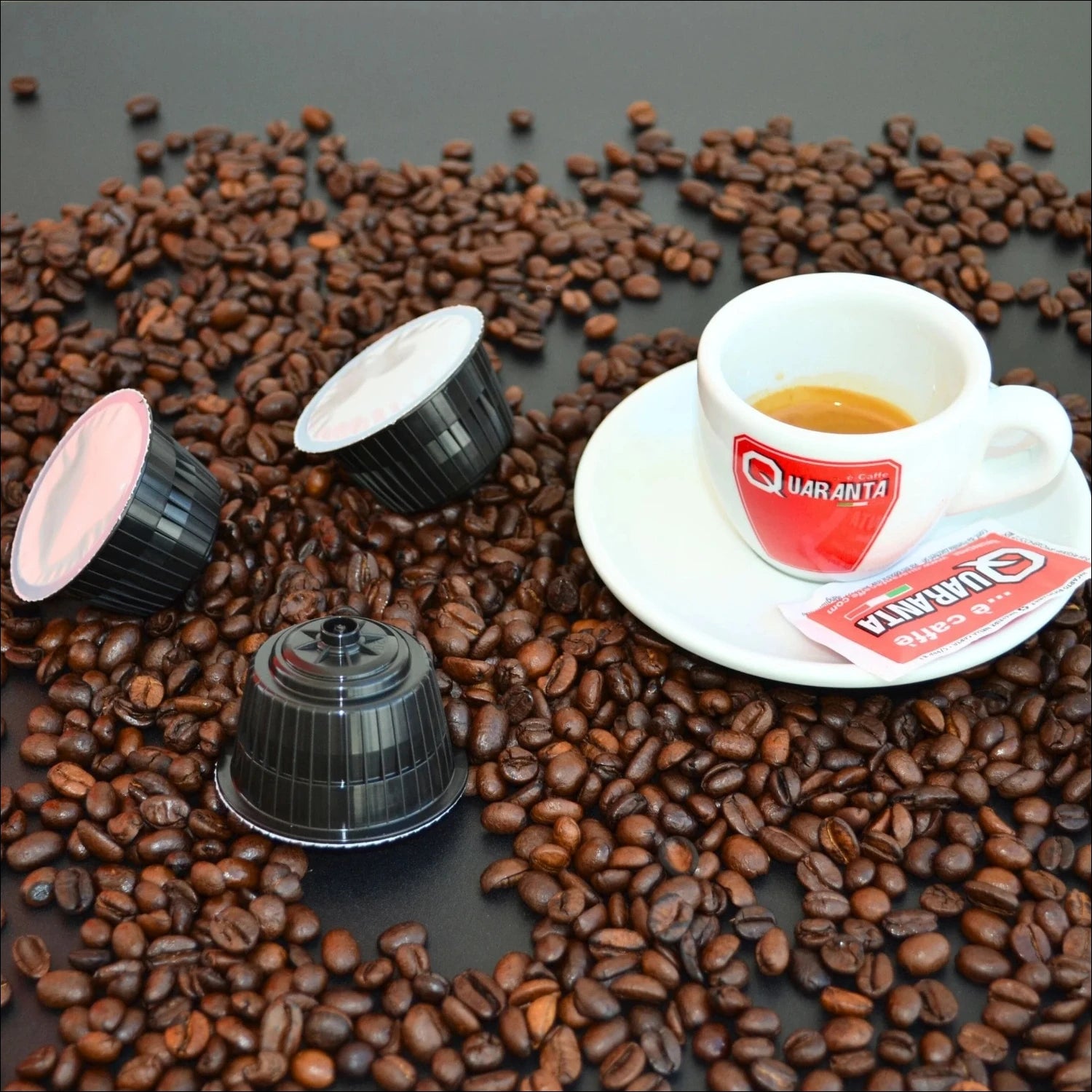 Eine Tasse Quaranta Caffè in einer Szenerie mit Kaffeebohnen und Nescafè Dolce Gusto Kapseln