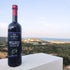 Quaranta Gusto Mirto-Likör-Flasche auf Sardinien bei Sonnenuntergang; im Hintergrund die Costa Smeralda.
